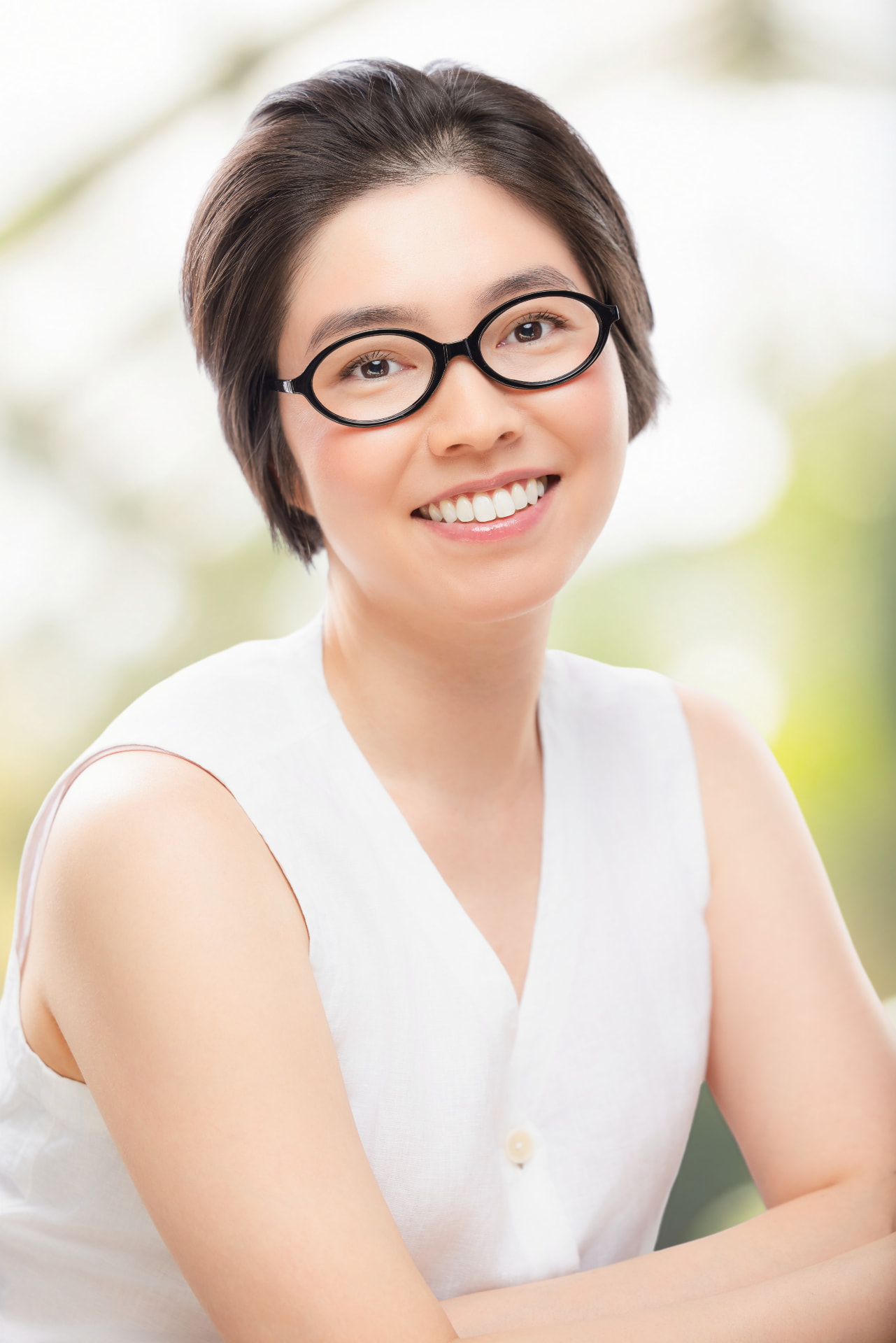 Mariko, smiling, with short hair and round black glasses
